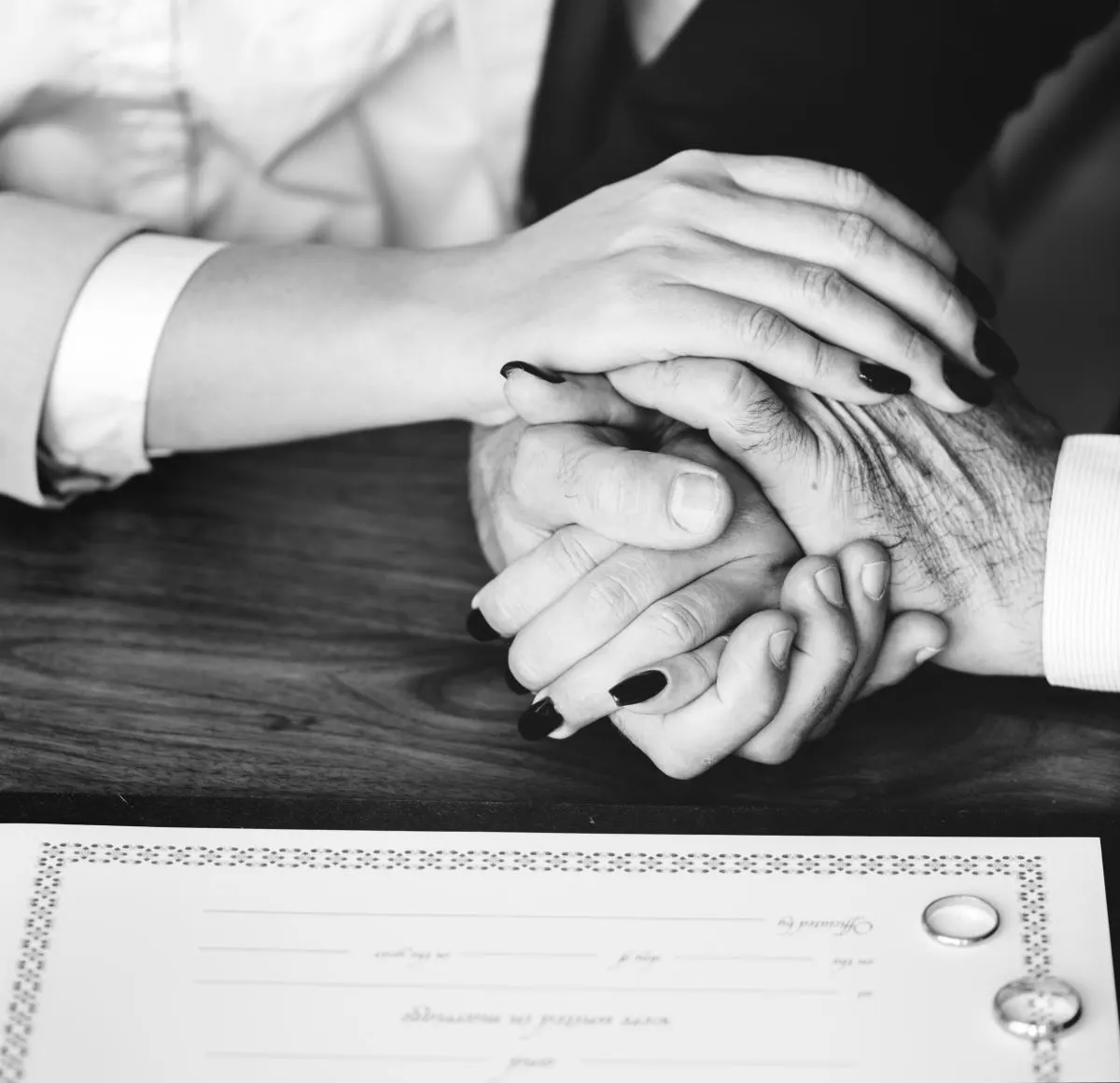 Twee handen die elkaar vasthouden boven een document, in zwart-wit.